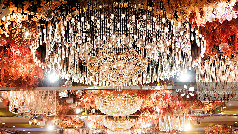 婚礼现场酒店吊顶下悬挂的圆形水晶灯的低角度视图图片素材