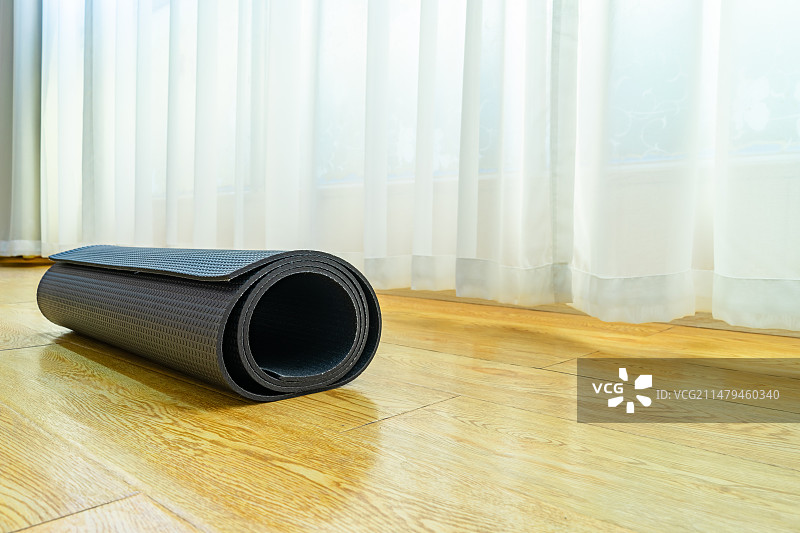 中国室内的瑜伽馆，木地板上的放置的黑色的展开的圆柱形瑜伽垫，室内无人图像摄影图片素材