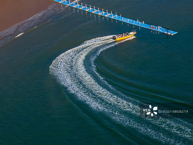 航拍“中国八大最美海岸线”之一冬季福建泉州惠安崇武西沙湾金色沙滩及海面快艇及浪花图片素材