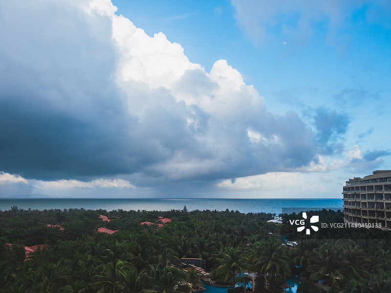 多云天空下三亚海边密林中的度假酒店图片素材