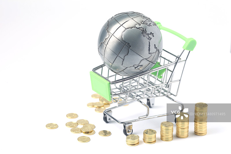 地球仪放在购物车里和硬币在白色背景前图片素材