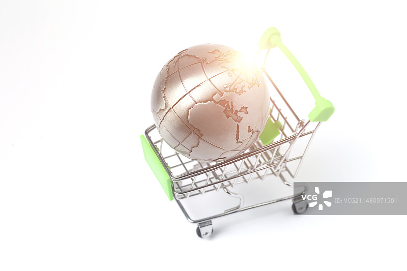地球仪放在购物车里和硬币在白色背景前图片素材