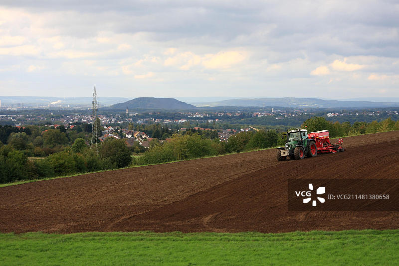 秋季田野中用电动犁的农民，背景是弗尔克林根图片素材