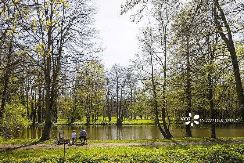 春季的城堡公园，垂钓者在城堡池塘边图片素材