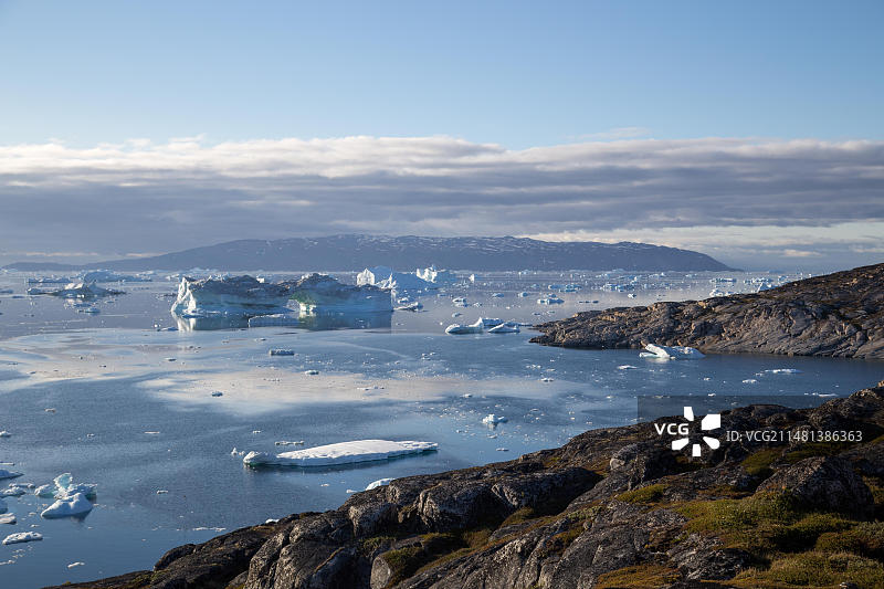 格陵兰岛伊卢利萨特午夜阳光下的海岸线与冰山图片素材