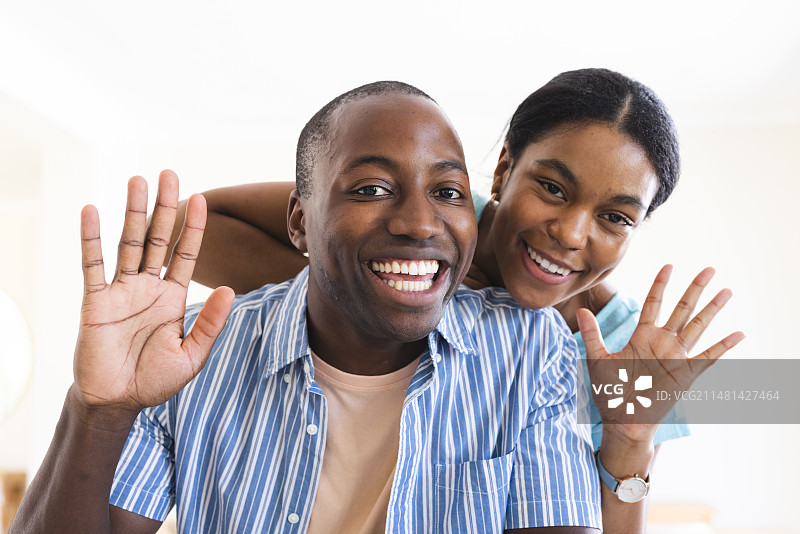 年轻的非裔美国男人和混血女人在智能家居上进行视频通话，愉快地挥手致意图片素材