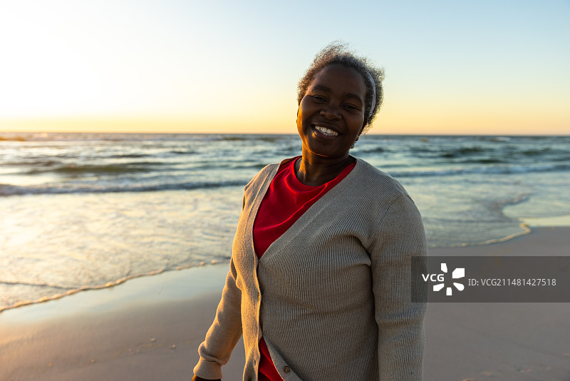 一位年长的非裔美国妇女在海滩欣赏日落美景图片素材