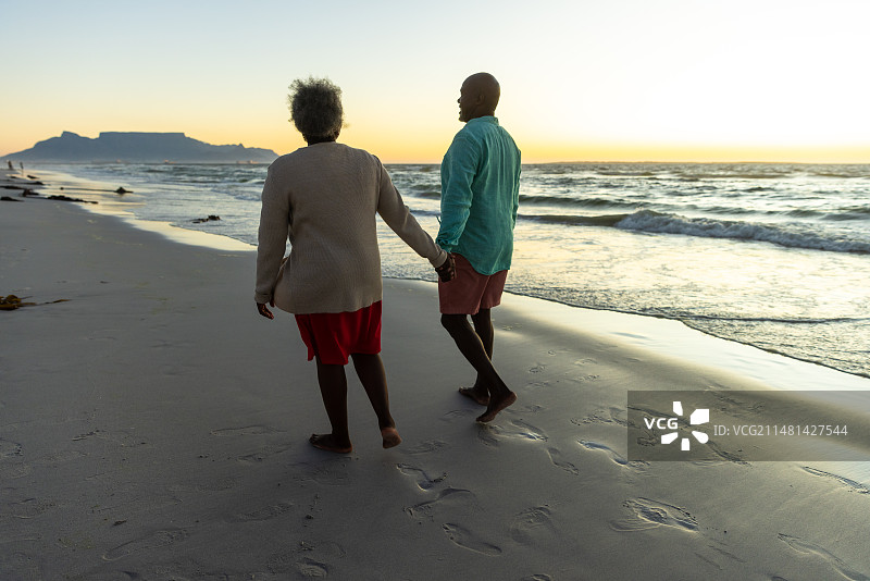 年长的非裔美国夫妇在日落时享受海滩散步图片素材