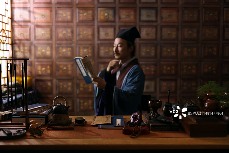 一个古代中医坐在药柜前读古书图片素材