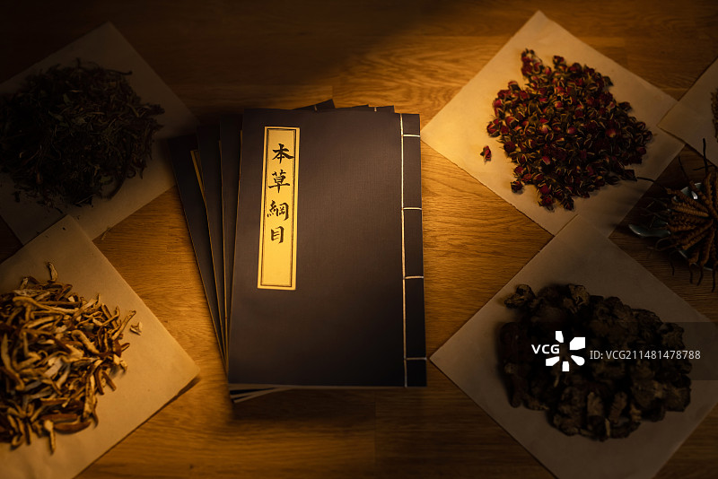 桌子上的本草纲目和中药材,暗色调图片素材