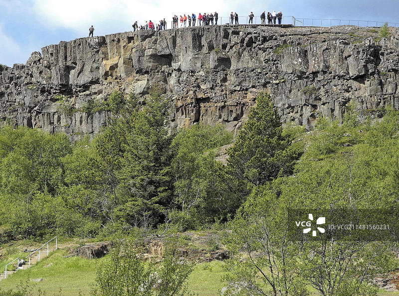 游客们站在冰岛西南部议会旧址国家公园的一块岩石上。这个国家公园被联合国教科文组织列为世界遗产。冰岛首都地区，欧洲图片素材