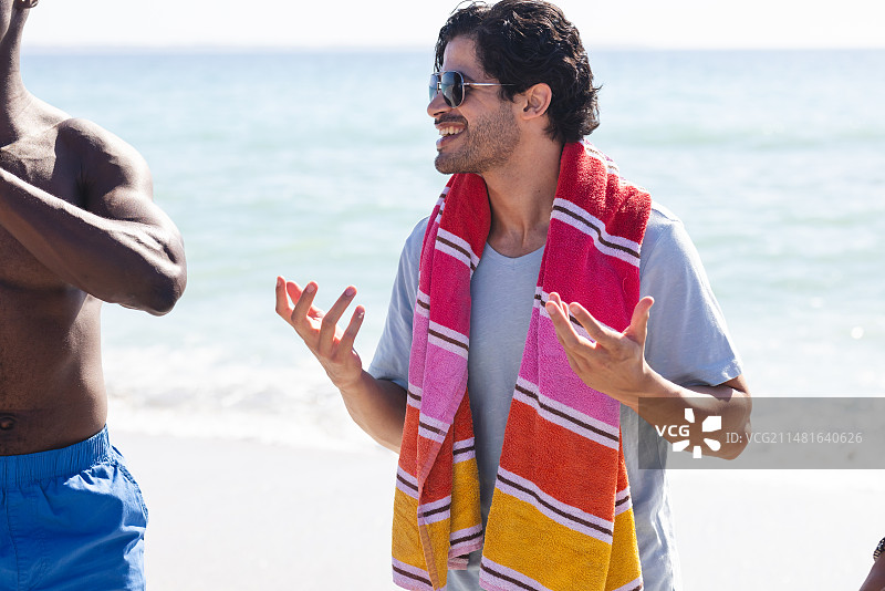 年轻的非裔美国男子在海滩上与混血男子聊天图片素材