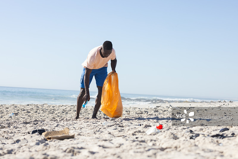 年轻的非洲裔男人在海滩清理垃圾图片素材