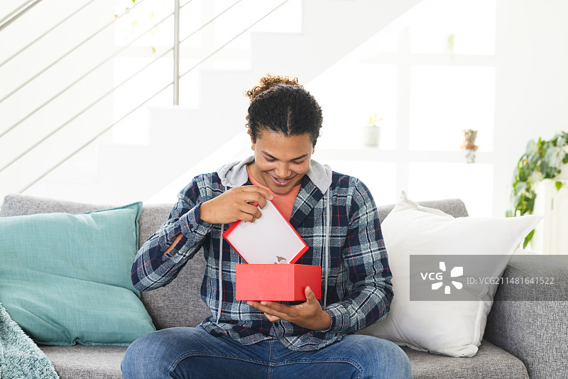 在家中通过视频通话打开礼物的年轻混血男人图片素材