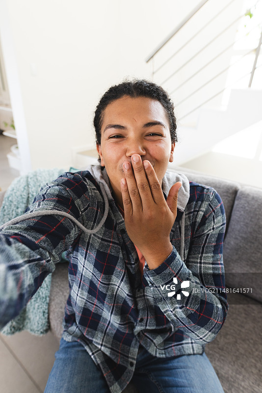年轻混血男人在家中视频通话时开怀大笑，留有文案空间图片素材