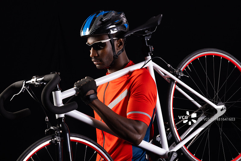 在黑色背景上拿着公路自行车的非裔男人，带文案空间图片素材