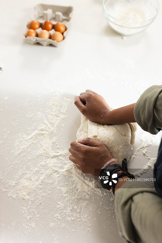 年轻非洲裔女人在案板上揉面团图片素材