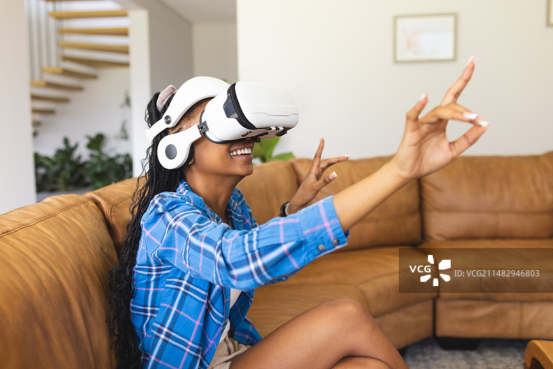 年轻的非裔美国妇女在客厅里使用VR头显图片素材