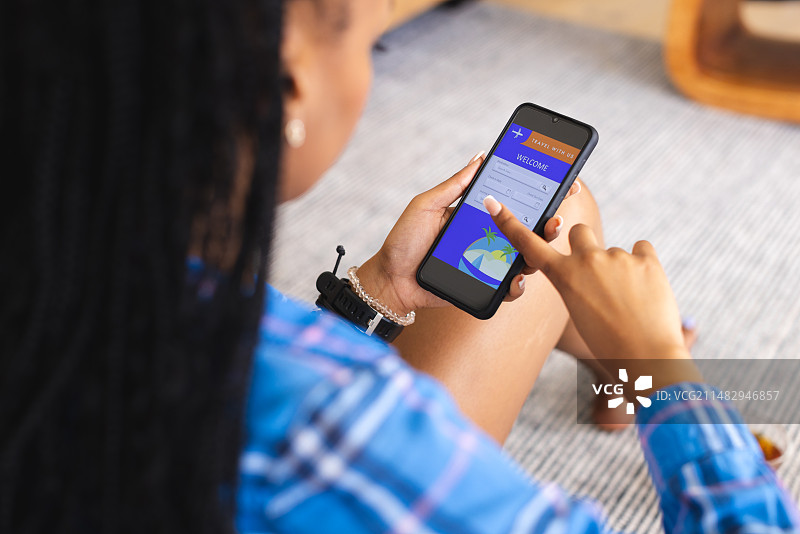 年轻的非裔美国妇女使用智能手机在线预订假期图片素材