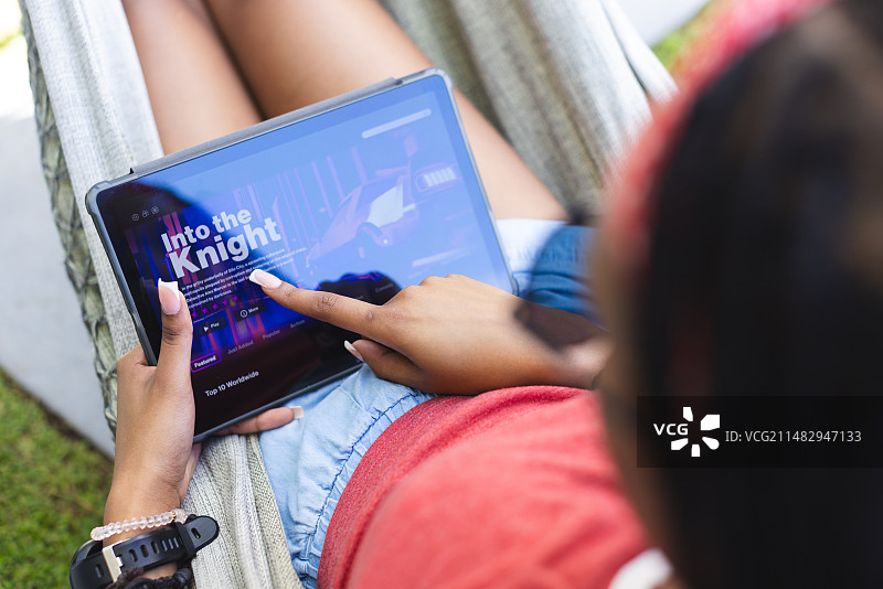 在户外平板电脑上观看视频的年轻非裔美国女性图片素材