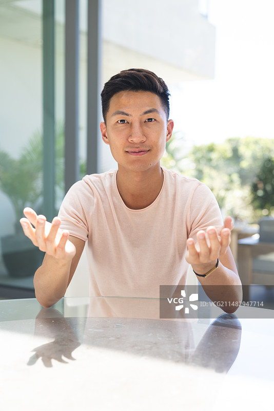 年轻的亚洲男人在家中视频通话时做手势交谈图片素材