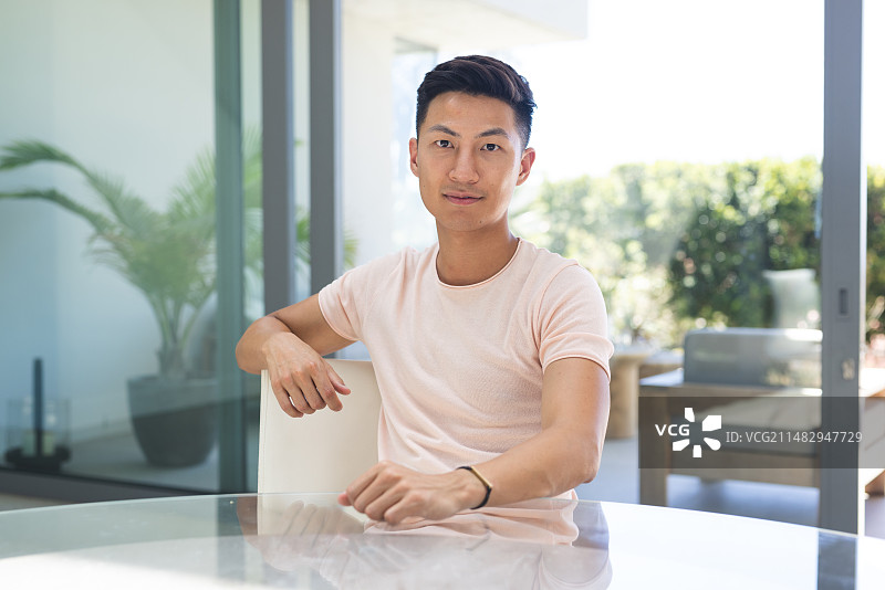 年轻的亚洲男人坐在室内现代桌旁进行视频通话图片素材