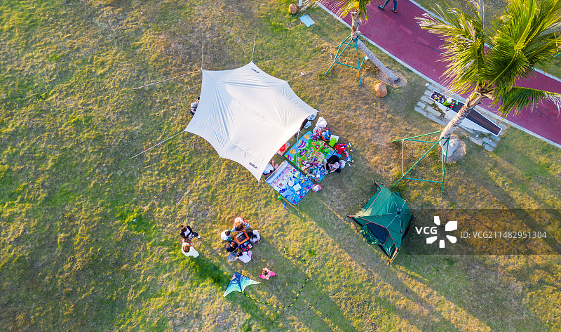 海南三亚春季小洲岛复绿公园阳光、草坪上的露营放风筝的开兴市民游客与家人图片素材