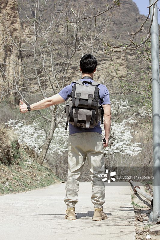 青年男子户外旅行做手势打车图片素材