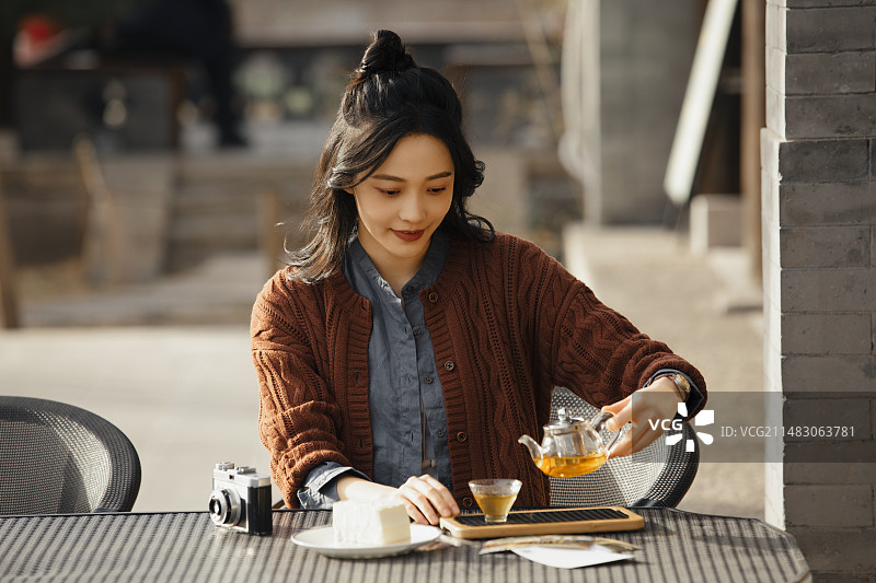 青年女子城市旅行在户外饮品店喝茶吃甜品休息图片素材