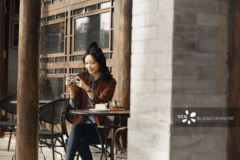 青年女子城市旅行在露天饮品店喝茶休息拍照图片素材