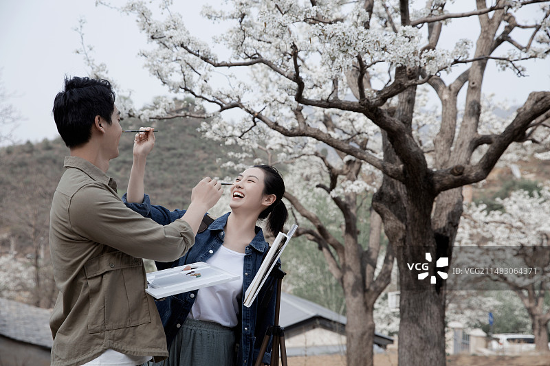 甜蜜情侣户外旅行写生打闹图片素材