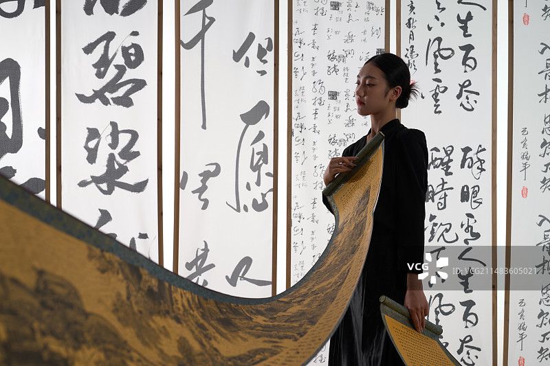一位身穿民族服饰美女拿着古典式卷轴图片素材