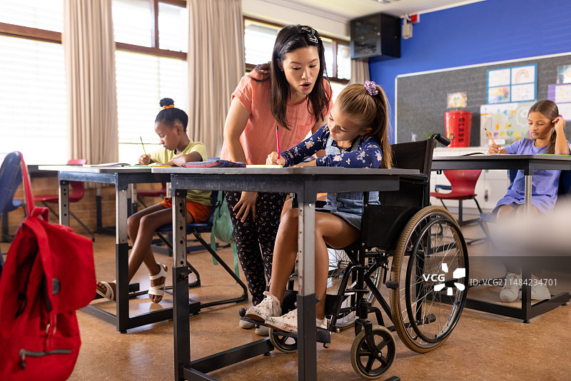亚洲教师在课后辅导坐在轮椅上的白人女孩图片素材