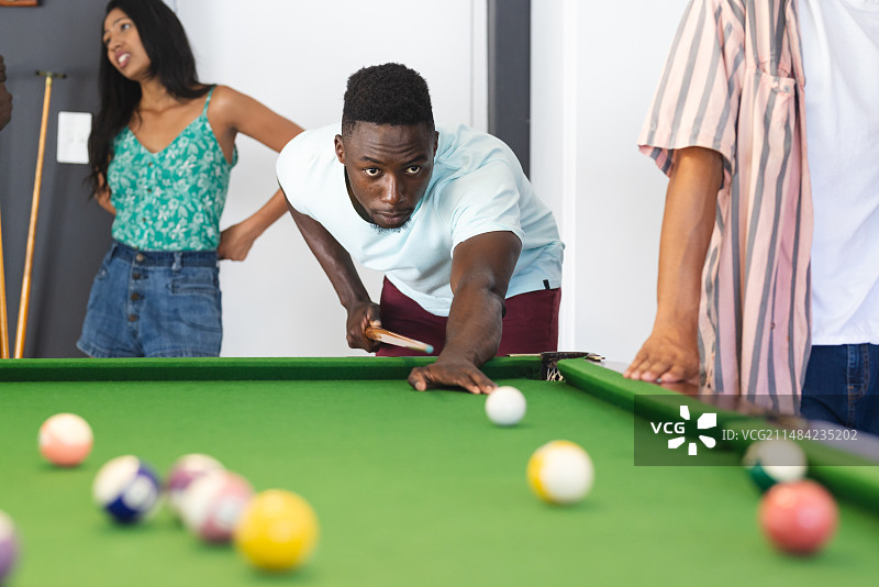 年轻的非裔美国男子专注打台球，年轻的混血女子观看图片素材