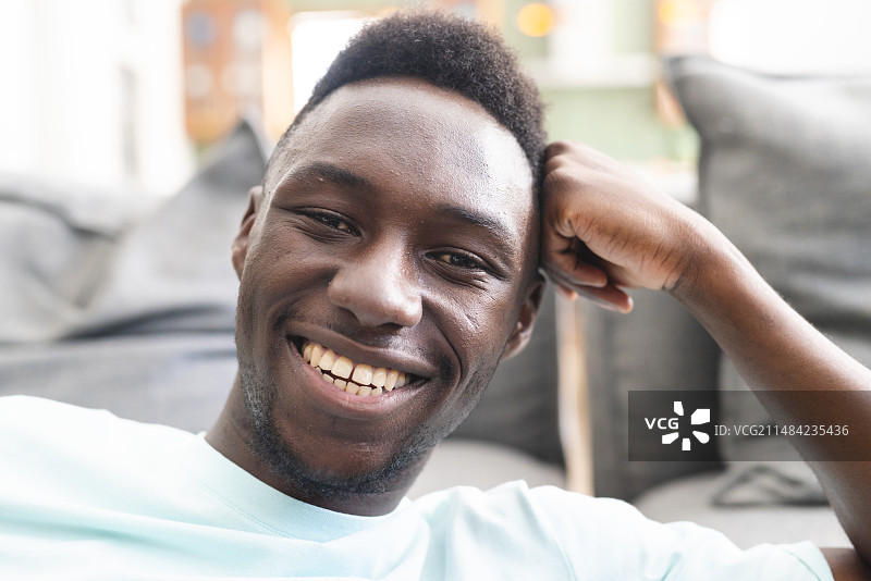 在休闲室内环境中休息的笑容灿烂的年轻非裔美国人图片素材