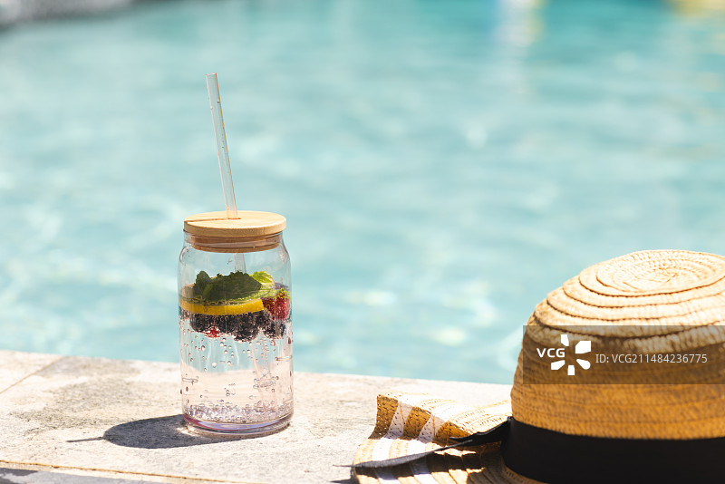 水果浸泡水罐和草帽在泳池边图片素材