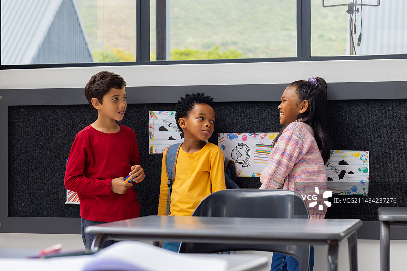 在学校教室里，混血男孩与一个非裔美国人男孩和一个混血女孩交谈图片素材
