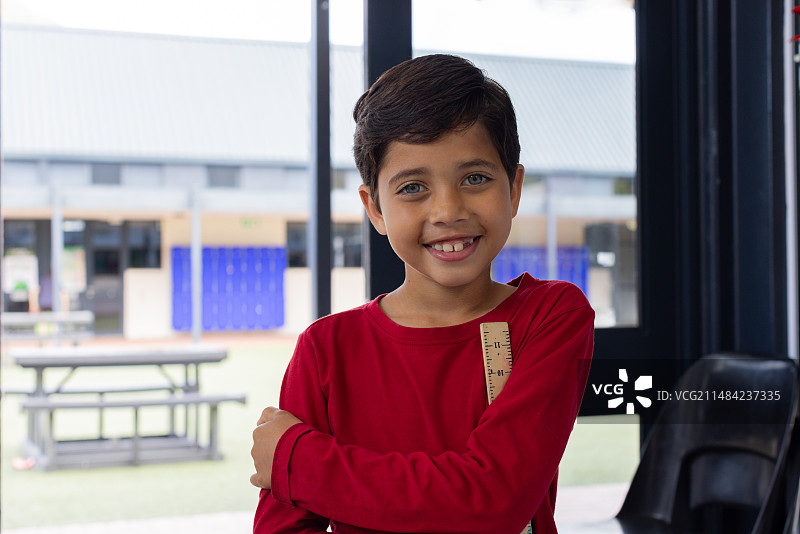 穿着红衬衫，在学校自信微笑的混血男孩图片素材