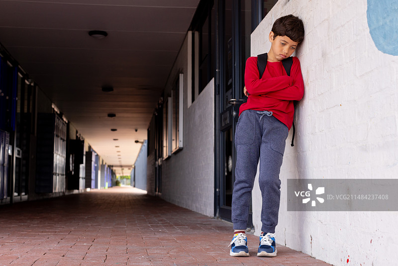 混血男孩在学校走廊靠墙沉思图片素材