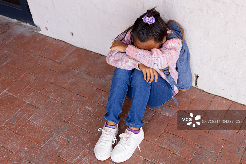 混血女孩看起来很沮丧，坐在地上，头低着，有文案空间图片素材