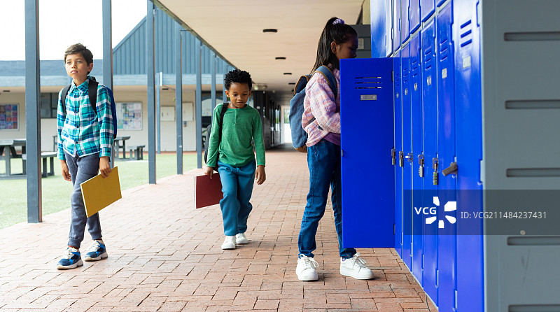 混血男孩和非裔美国男孩走过学校储物柜旁的混血女孩图片素材