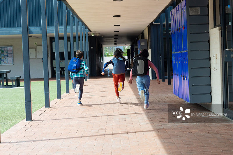 三个孩子在学校走廊里奔跑，右边是储物柜，留有复制空间图片素材