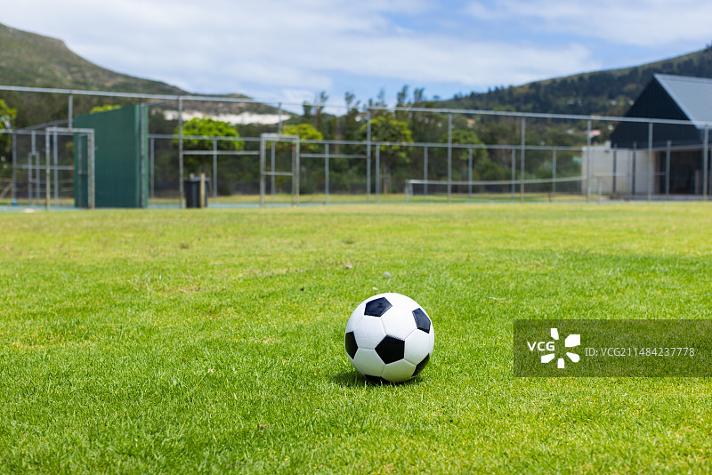 足球位于绿茵场上，背景是山脉，带有文案空间图片素材