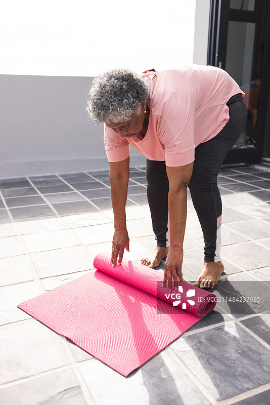 卷起粉色瑜伽垫的灰发老年混血妇女图片素材