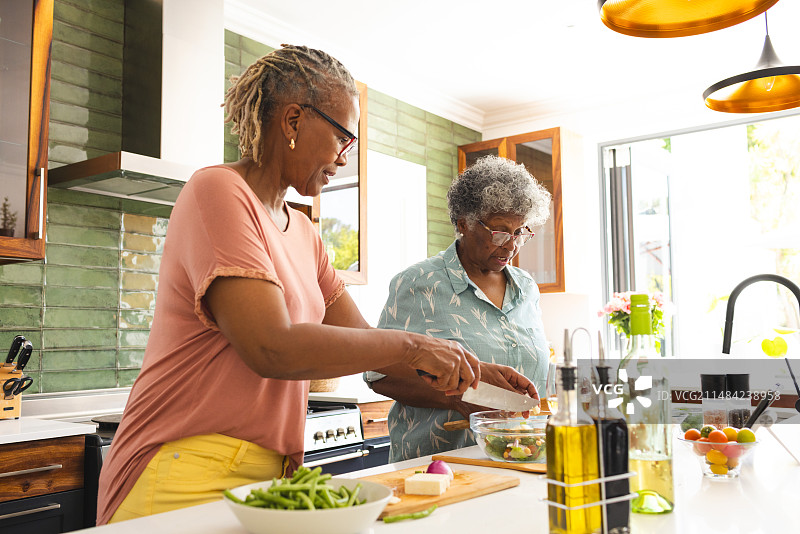 年长的非洲裔女人和年长的混血女人在厨房一起做饭图片素材
