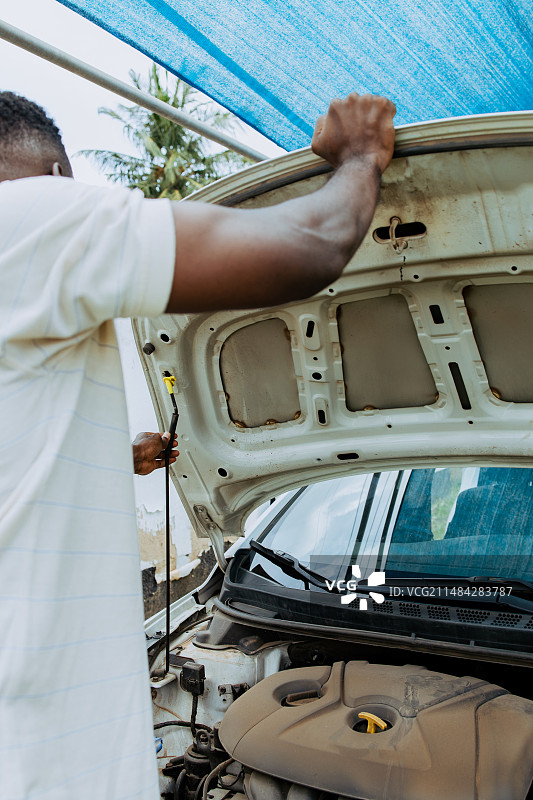 站在废弃汽车旁的男子，阿克拉，加纳图片素材