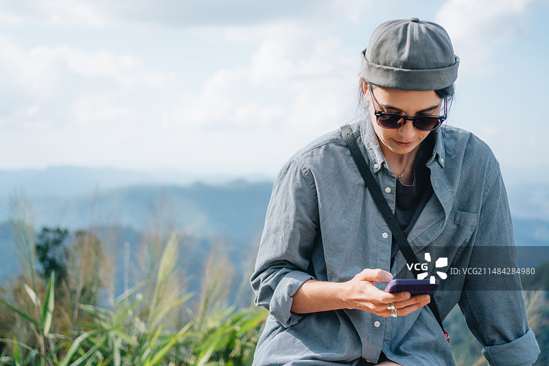 年轻女子在泰国山顶靠着天空使用手机图片素材
