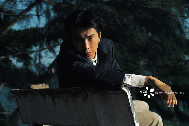 坐在越南公园长椅上的年轻男人肖像图片素材