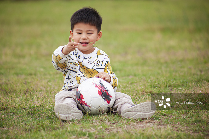 草地上踢足球的小男孩图片素材