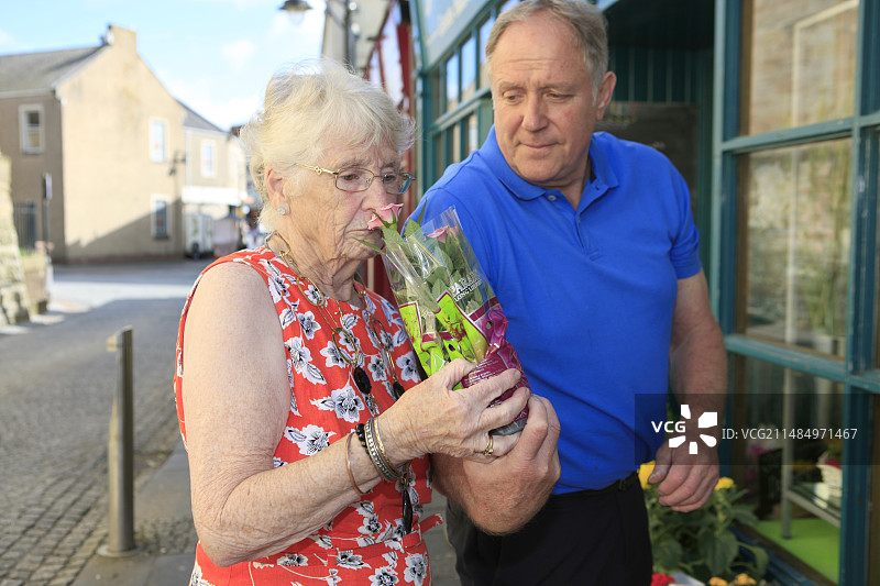 患有痴呆症的女人在闻花图片素材